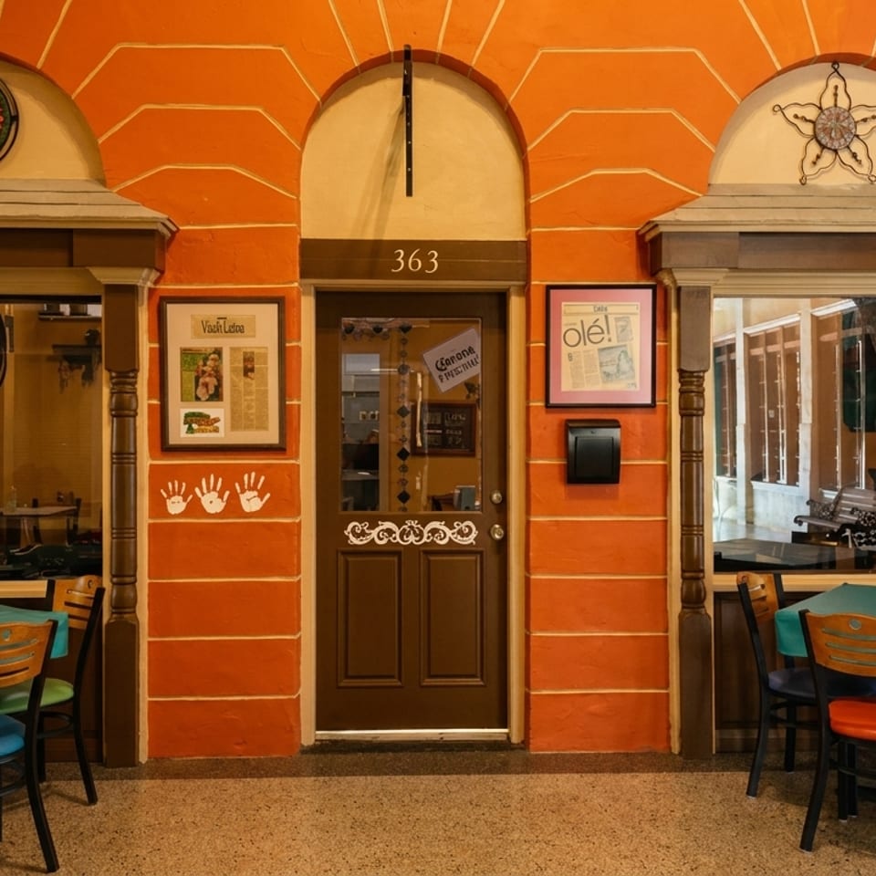 Vibrant orange restaurant facade with a brown door, two windows, and outdoor dining tables.