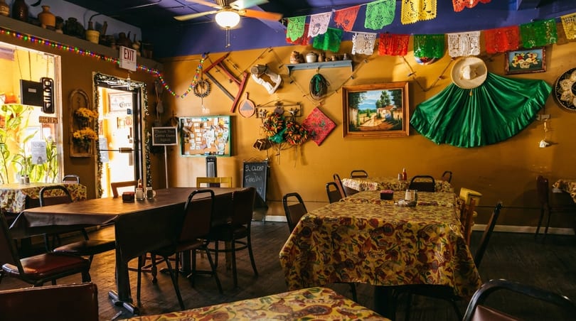 Colorful Mexican restaurant interior with decorated tables, festive banners, and cultural wall art.
