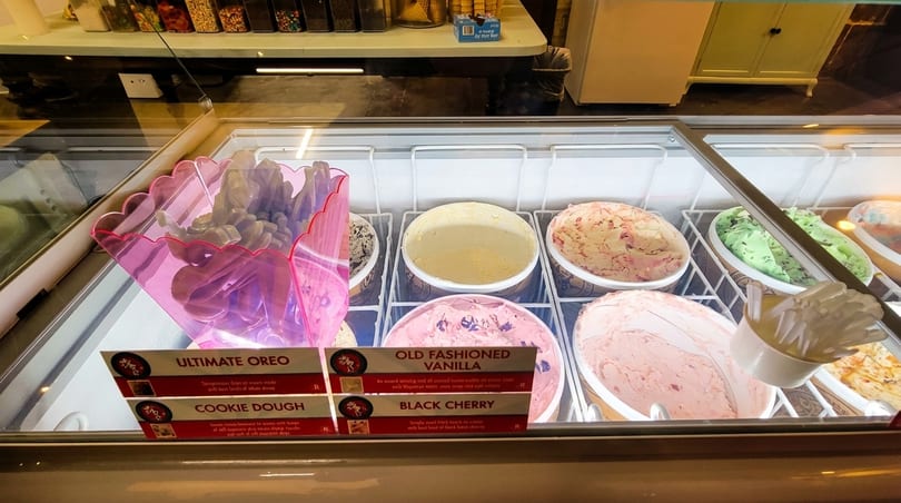 A brightly lit ice cream display case with various flavors and topping options.